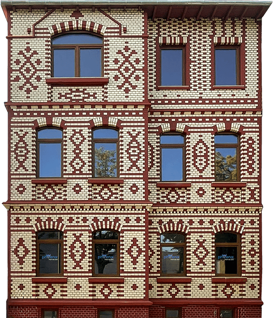 Die Fassade des Phoenix Homecare-Gebäudes mit ihren komplizierten roten und weißen Ziegelmustern weist Reihen von rechteckigen und bogenförmigen Fenstern auf.